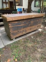 Overall view of wooden box with lid on casters