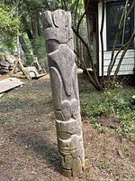Full view of carved basswood pole standing upright outdoors