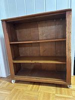Front view of three-shelf pine bookcase on casters