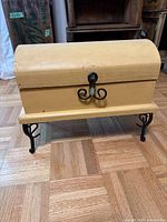 Front view of yellow wooden chest on black metal legs