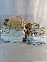 Two stacks of assorted folded linens showing variety of textures and colours