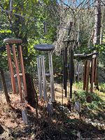 Three metal tube wind chimes in copper, silver and black finishes hanging outdoors