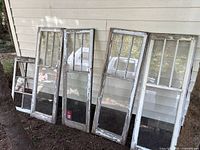 All five wood windows leaning against siding