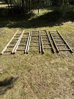 Five wooden ladders laid out on grass