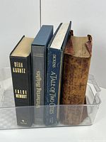 Four books in clear bin showing spines