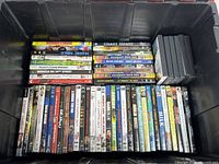 Overview of approximately 50 DVD titles in plastic tote showing spines and some cover art