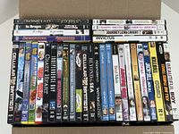 Open box showing 34 DVD movie cases, spines visible