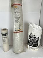 Three rolls of vapour-barrier plastic sheeting standing side by side