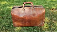 Front view of brown leather doctor’s bag on grass