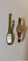 Two gold-tone wristwatches side by side