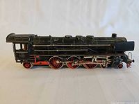 Left side view of black/red Marklin steam locomotive showing wheels and markings