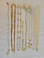 All necklaces, rosary, earrings and ring laid out on cloth