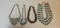 Four necklaces laid out side by side showing full lot