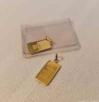 Front view of both gold bar pendants, one sealed, one loose