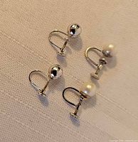 Two pairs of screw-back earrings laid flat on fabric