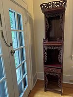 Full view of tall carved rosewood altar stand beside door
