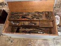 Open wooden chest with tray showing wrenches, pliers, chisels