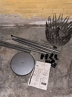All components laid out: base, poles, carousel rack, connectors, instruction sheet