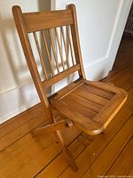 Full view of folded-out wood chair showing back slats, seat, and legs