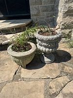 Two cement planters side by side on stone patio