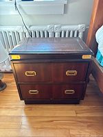 Front view of one nightstand showing top surface, hardware and drawer fronts
