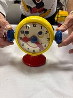 Front view of Ambi Toys Tick Tock Clock on red pedestal