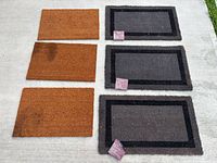 Set of six door mats arranged, three brown and three grey bordered mats, product tags visible