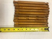 Stack of full-length Lincoln Logs beside tape measure showing ~9 in. length