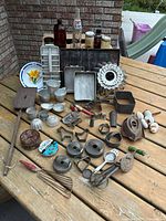 Full lot overview on picnic table showing bakeware, utensils, bottles and plate