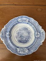 Front view of blue transferware plate with pastoral scene and scalloped rim