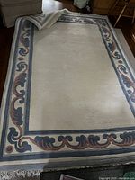 Full view of rug showing cream field, colored border, fringe