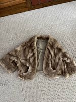 Full view of mink bolero jacket laid flat showing front, sleeves, and pockets