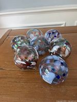 Seven multicoloured glass ball ornaments on wooden surface