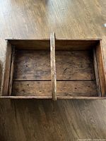 Top view of empty wooden toolbox showing central handle and interior