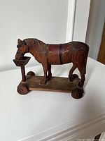 Left side view of carved wooden horse on wheeled base