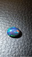 Oval cabochon black opal showing multicolor play-of-color