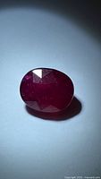 Front view of oval ruby showing faceted surface and color