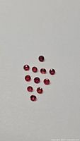 Group of 12 round red rubies on light background