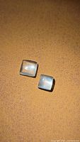 Two cushion cabochon Aquamarine stones on brown surface