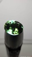Front lit view showing green moss inclusions in oval cabochon