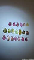 All tourmaline gemstones arranged in rows showing variety of colors and leaf cuts