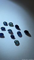 Group of ten oval blue sapphires on white background