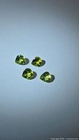 Four apple green peridot gemstones on light background