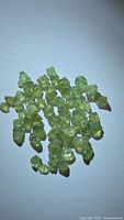 Group of rough demantoid garnet crystals spread on white surface