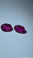 Pair of oval faceted rubies on white background