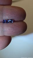 Three blue cushion-cut gemstones on fingertips
