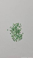 Pile of small green round faceted stones on white background