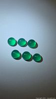 Six round vivid green cabochon gemstones arranged in two rows