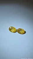 Pair of yellow oval-cut sapphires on white background