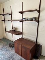 Full view of wall-mounted shelving unit with cabinet and extra legs on floor